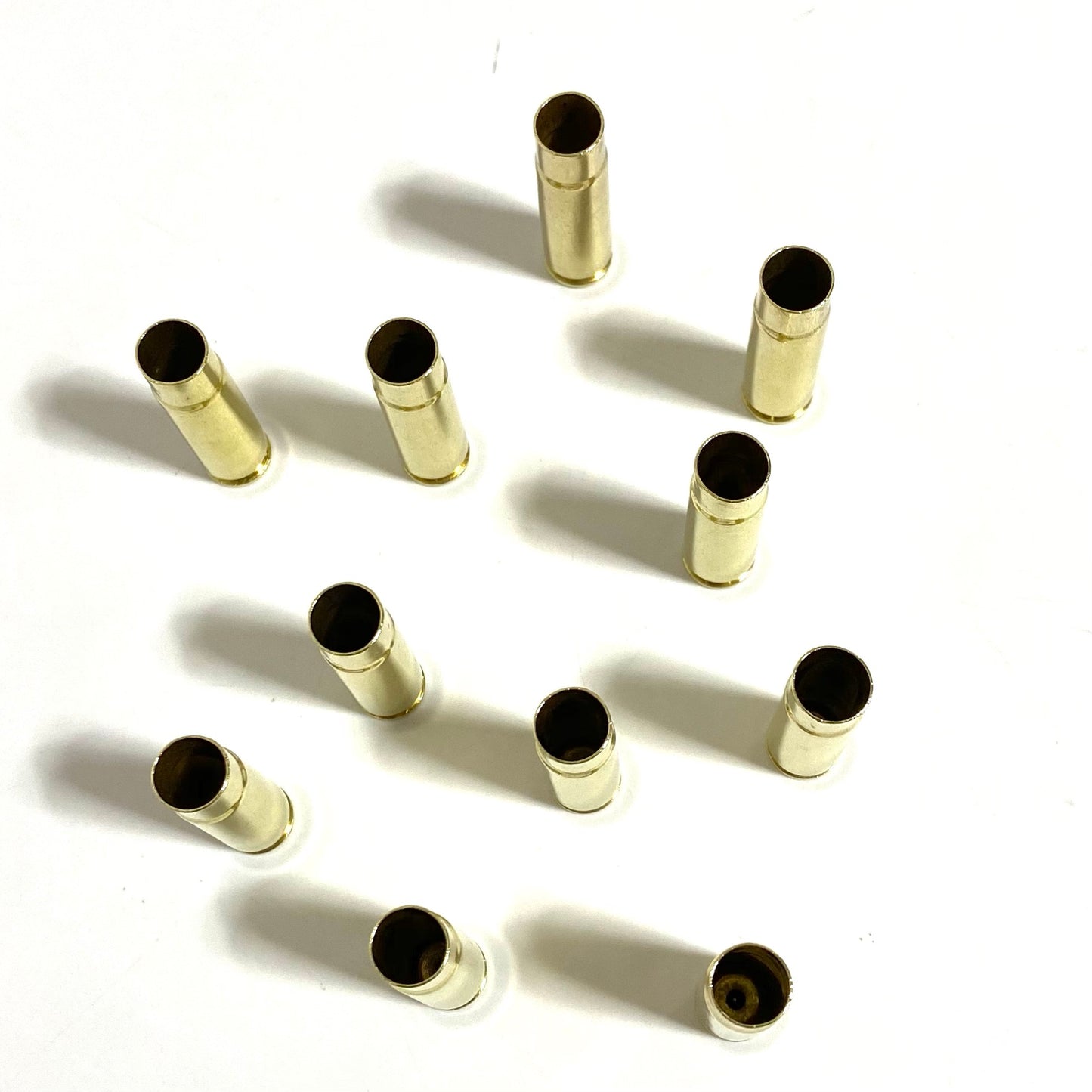 A collection of empty 300 Blackout brass rifle shells standing upright on a clean white surface.