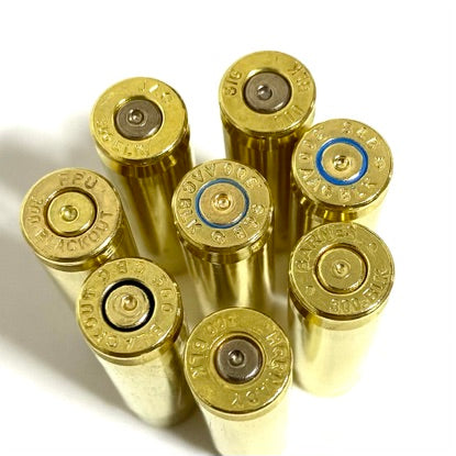 Close up view of the headstamps on multiple empty 300 Blackout spent brass casings standing upright.