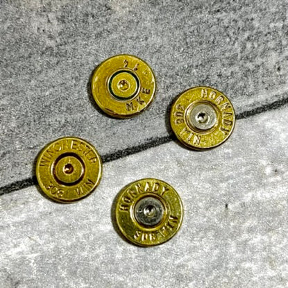 Four brass 308 casing slices with Winchester and Hornady headstamps on a cracked concrete surface