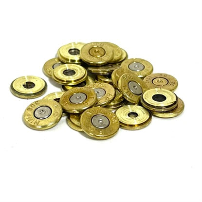Pile of 308 brass casing slices with mixed silver and gold primers, overhead view on white background