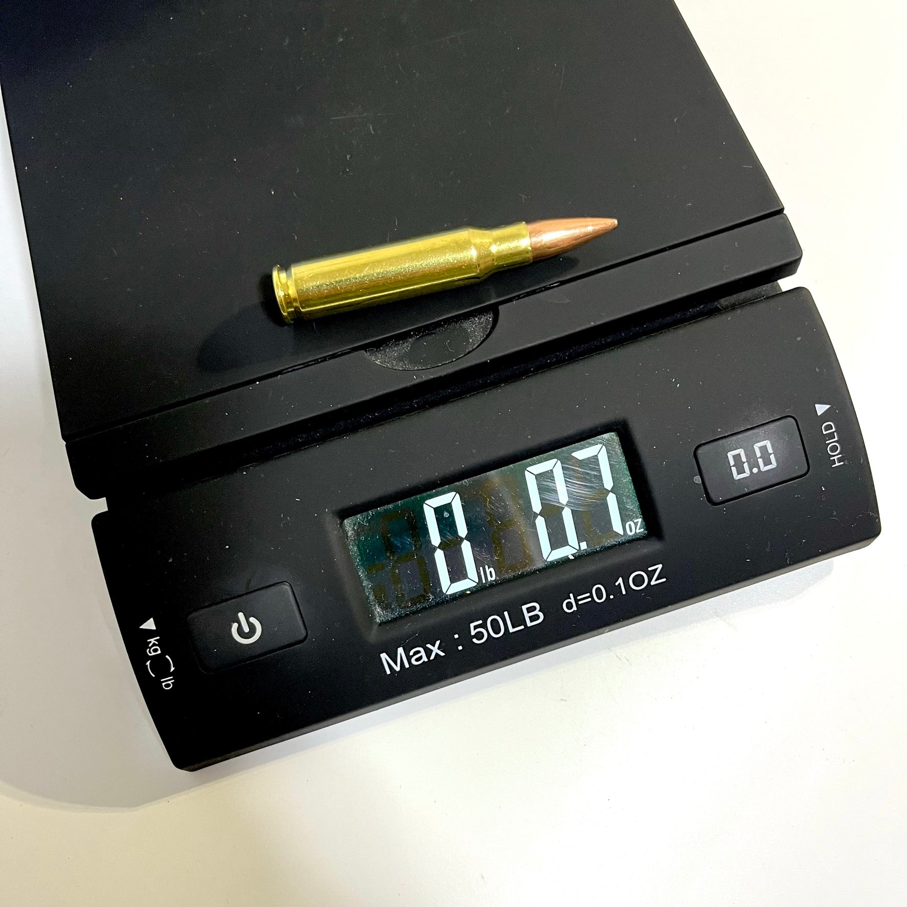 Single brass .308 snap cap on a digital scale reading 0 lb 0.7 oz