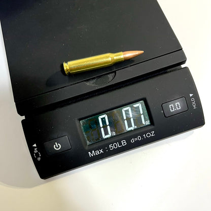 Single brass .308 snap cap on a digital scale reading 0 lb 0.7 oz