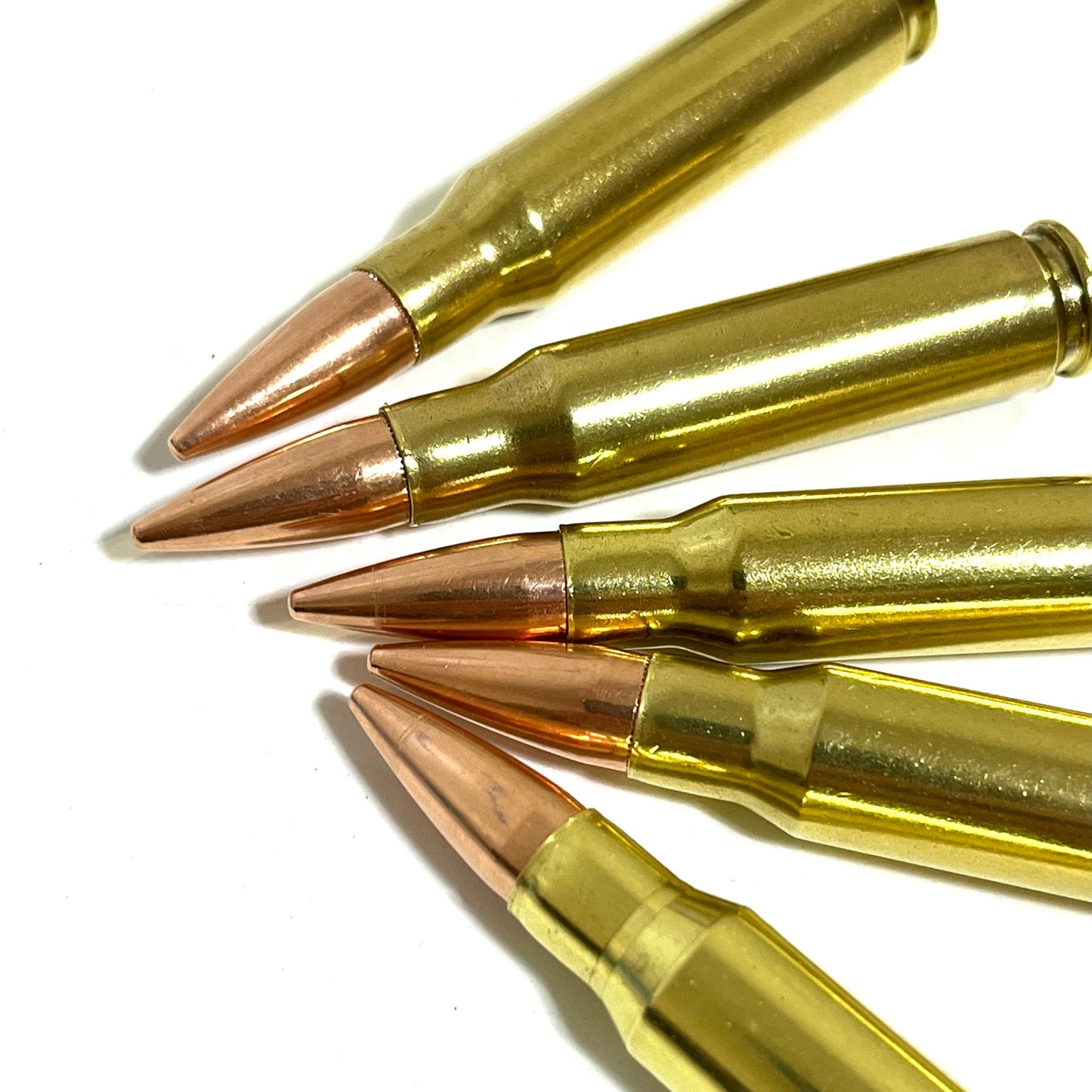 Five brass .308 snap caps with copper bullet tips fanned out in close-up on white background