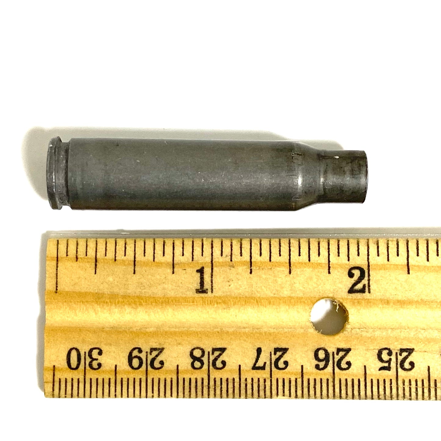 9 gray steel 308 casings standing upright viewed from above showing drilled primers