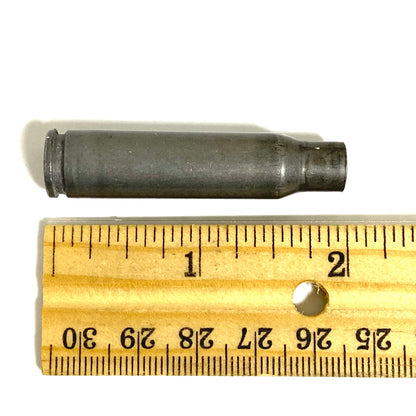 9 gray steel 308 casings standing upright viewed from above showing drilled primers