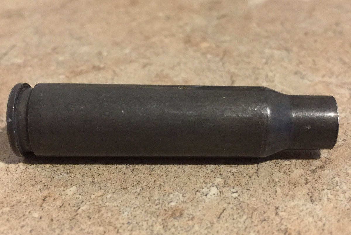 Single gray steel 308 casing lying on a stone surface