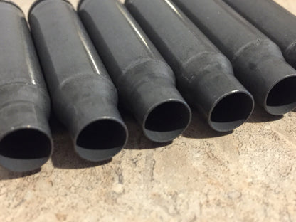 6 gray steel 308 casings lying in a row showing open mouths on a stone surface