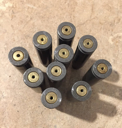 9 gray steel 308 casings viewed from the base showing small drilled holes in the primers