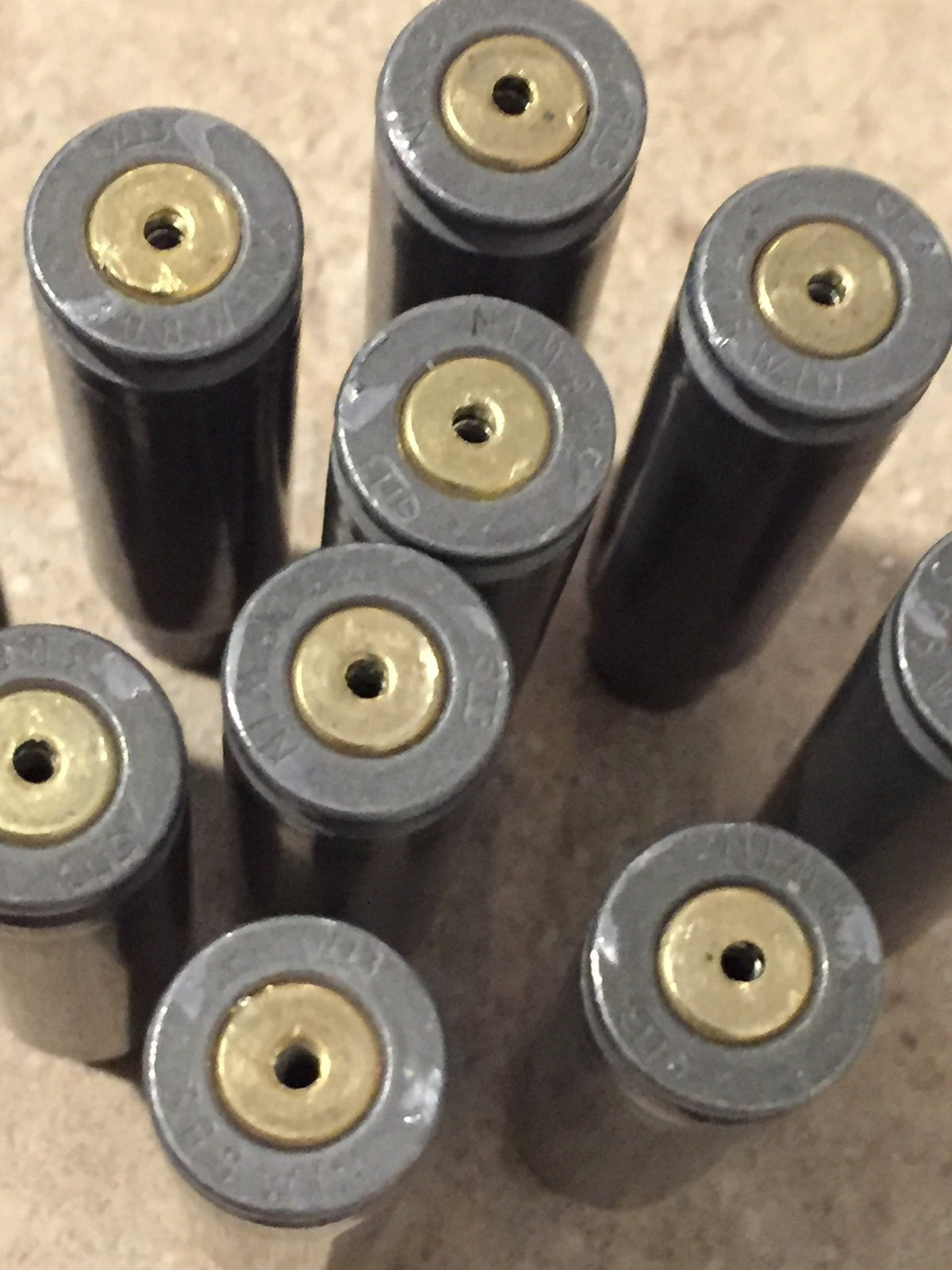 10 gray steel casings lying in a diagonal row on a stone surface