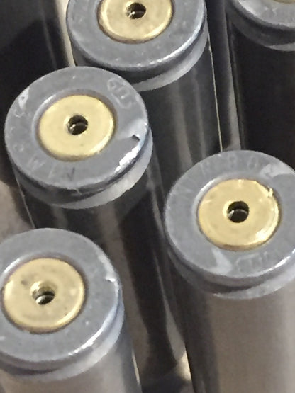 10 gray steel 308 casings lying in two rows on a stone surface