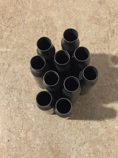 9 gray steel 308 casings with drilled primers clustered together on a stone surface