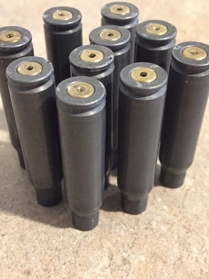 10 gray steel 308 casings lying in a diagonal row on a white background