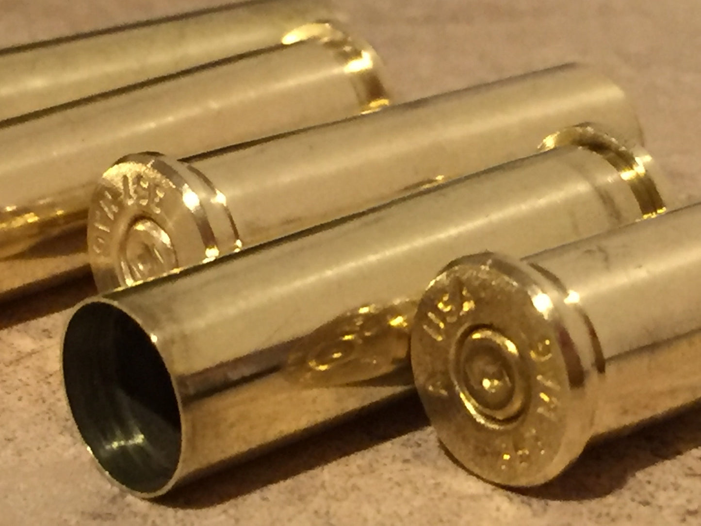 Extreme close-up of four polished 357 Magnum spent brass shells lying horizontally, one open mouth prominent and legible headstamp.