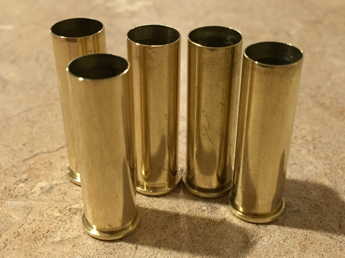 Five polished upright 357 Magnum brass cases standing on a light textured countertop, showing open top mouths.