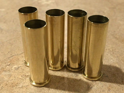 Five polished upright 357 Magnum brass cases standing on a light textured countertop, showing open top mouths.