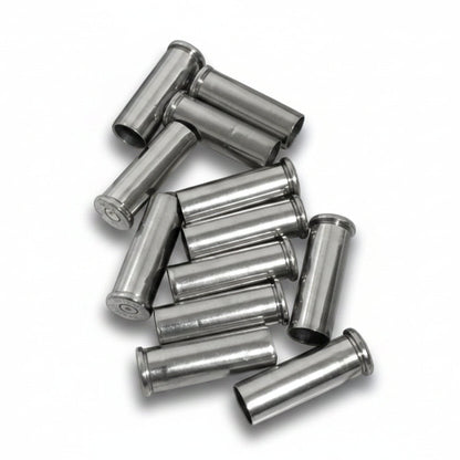A tightly clustered heap of used silver nickel shells resting on a weathered wood-plank surface.