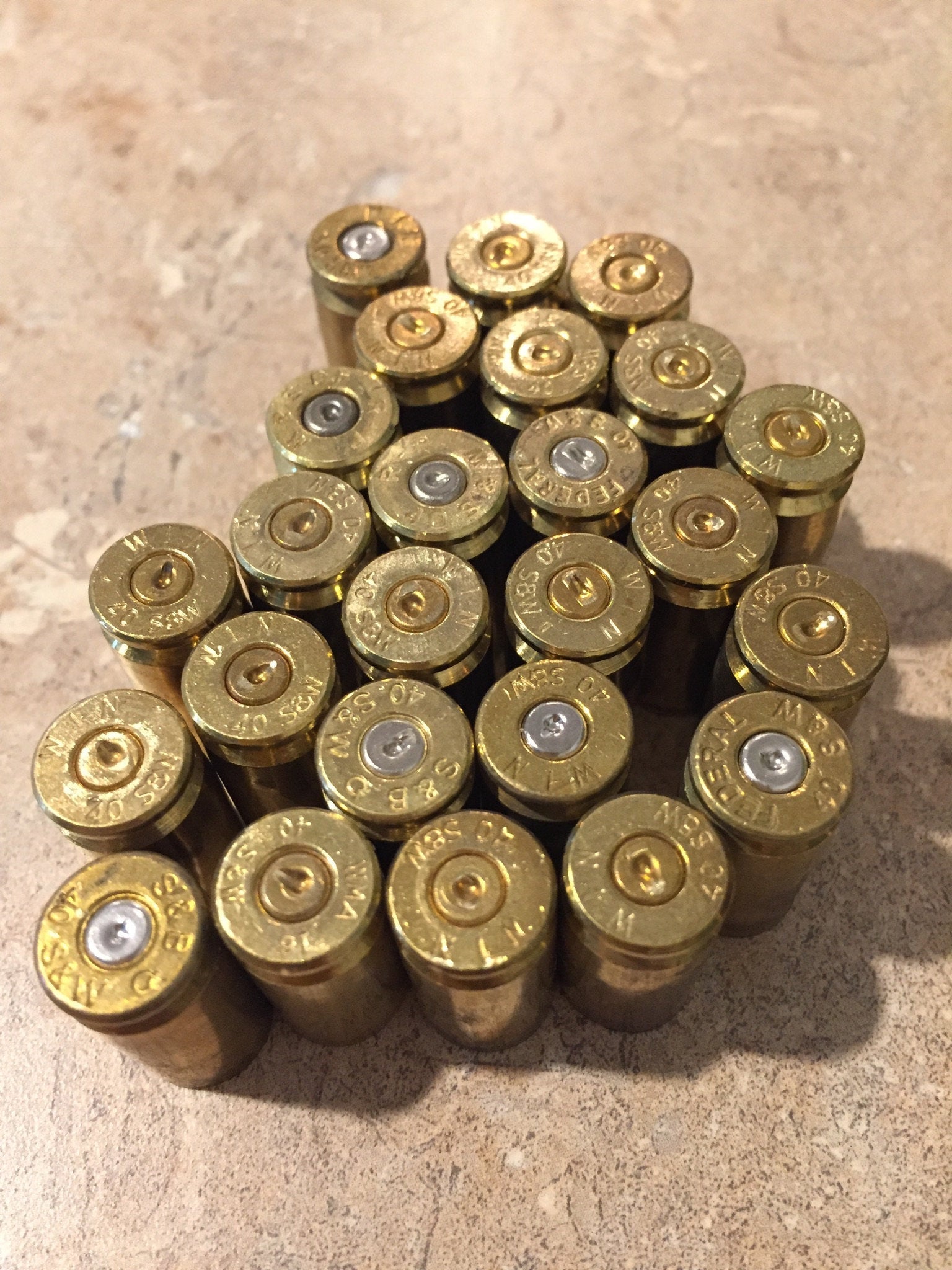 Cluster of gold .40 S&W brass casings viewed from above, showing headstamp markings and spent silver primers