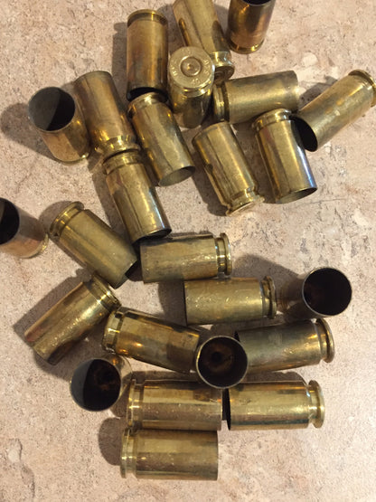 Pile of gold .40 S&W brass casings lying at angles on a stone surface, showing open mouths and headstamps