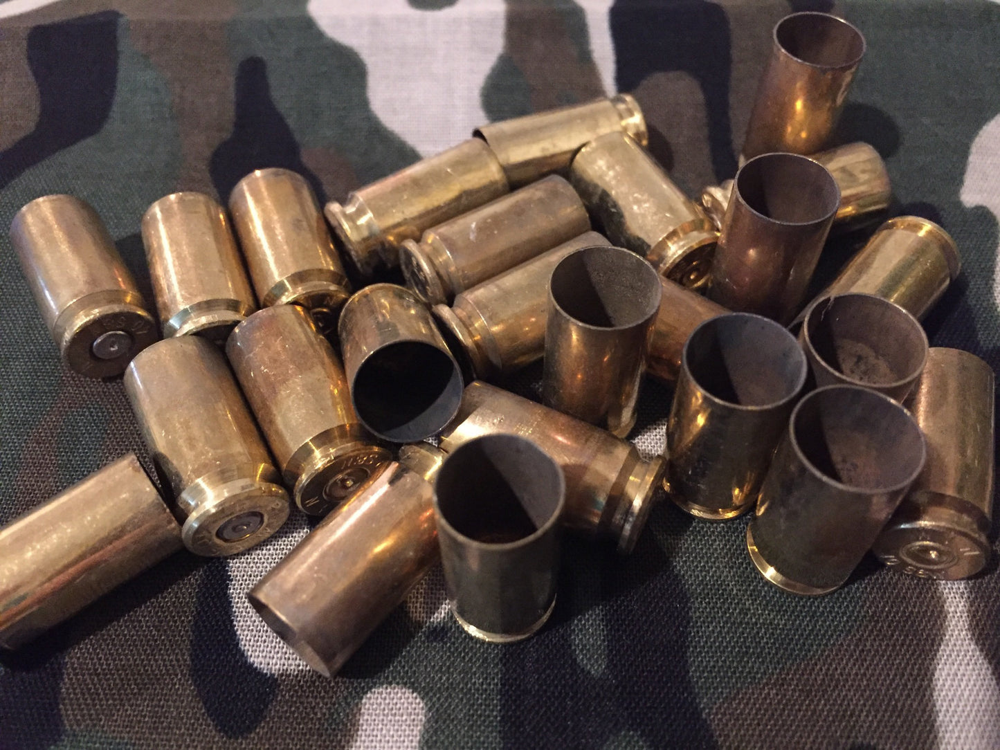 Pile of gold .40 S&W brass casings scattered on a camouflage fabric background