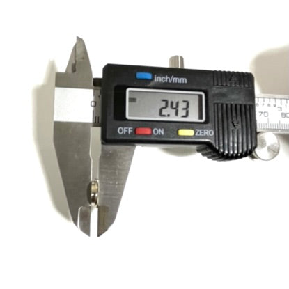 A single polished 40 S&W nickel bullet slice being measured by a digital caliper on a white surface, with the digital display reading 2.43. 