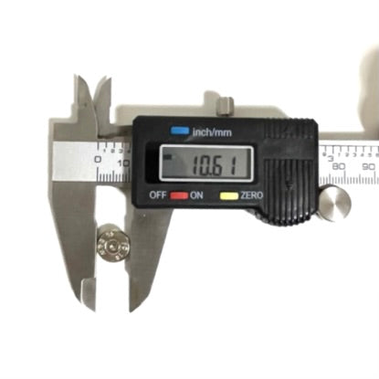A single polished 40 S&W nickel bullet slice being measured across its diameter by a digital caliper on a white surface, with the digital display reading 10.61. 
