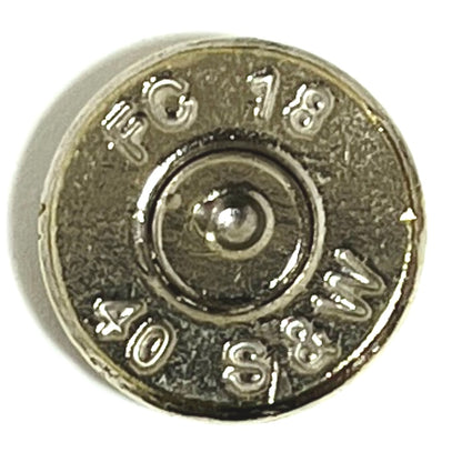 A macro close-up of a single polished 40 S&W nickel bullet slice with smooth edges on a white surface, focusing on the silver outer rim and the contrasting brass-colored center with a dark spent primer.