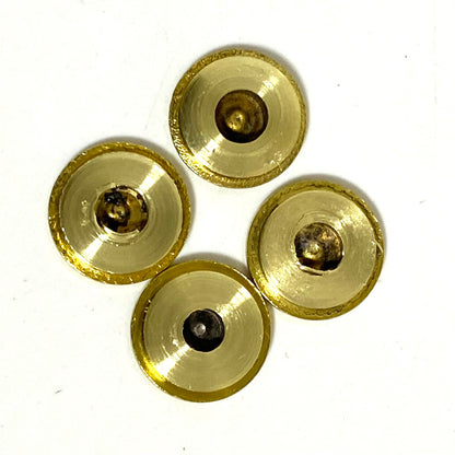 Four gold ammo slices arranged in a cluster, showing the concave interior side with tarnished centers.