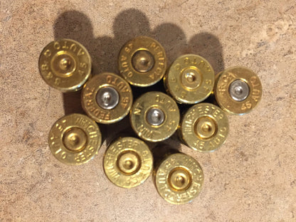 Cluster of ten uncleaned brass shell casings showing their headstamps.
