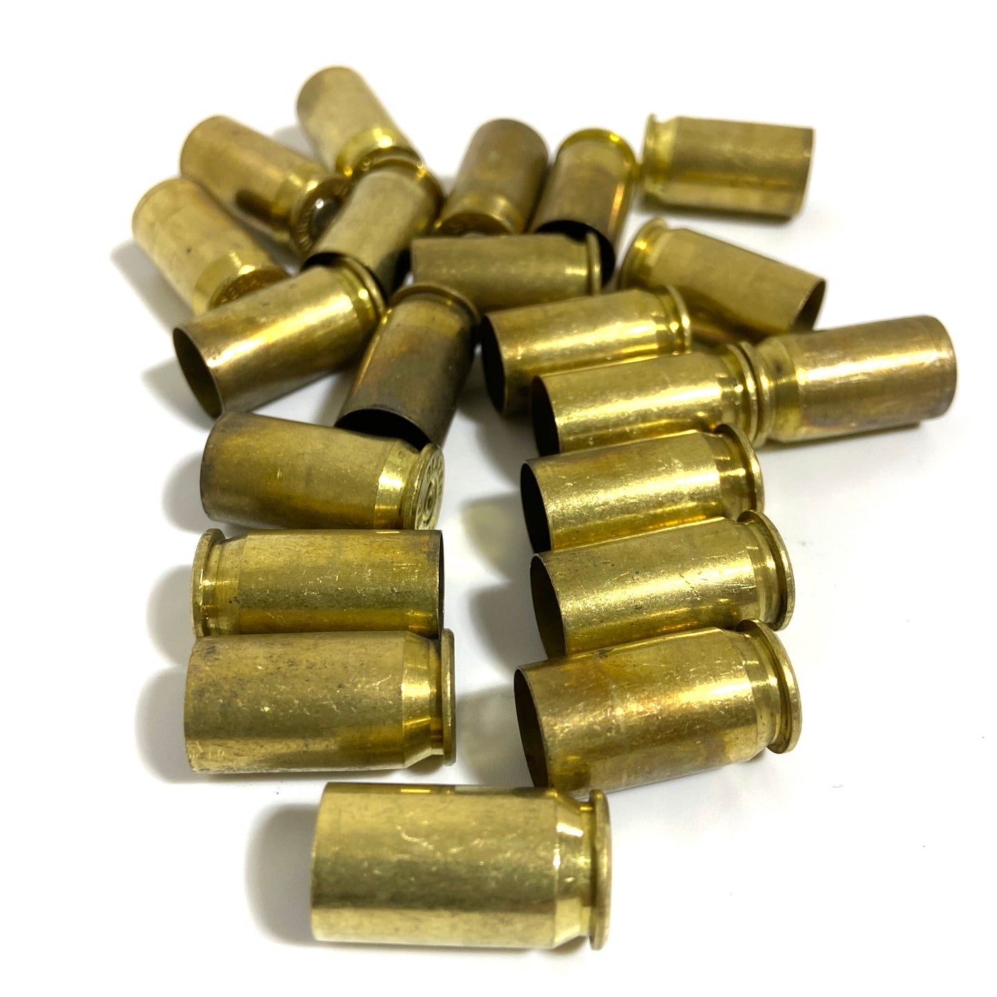 Loose pile of about 20 brass .45 ACP casings scattered on white background in mixed orientations