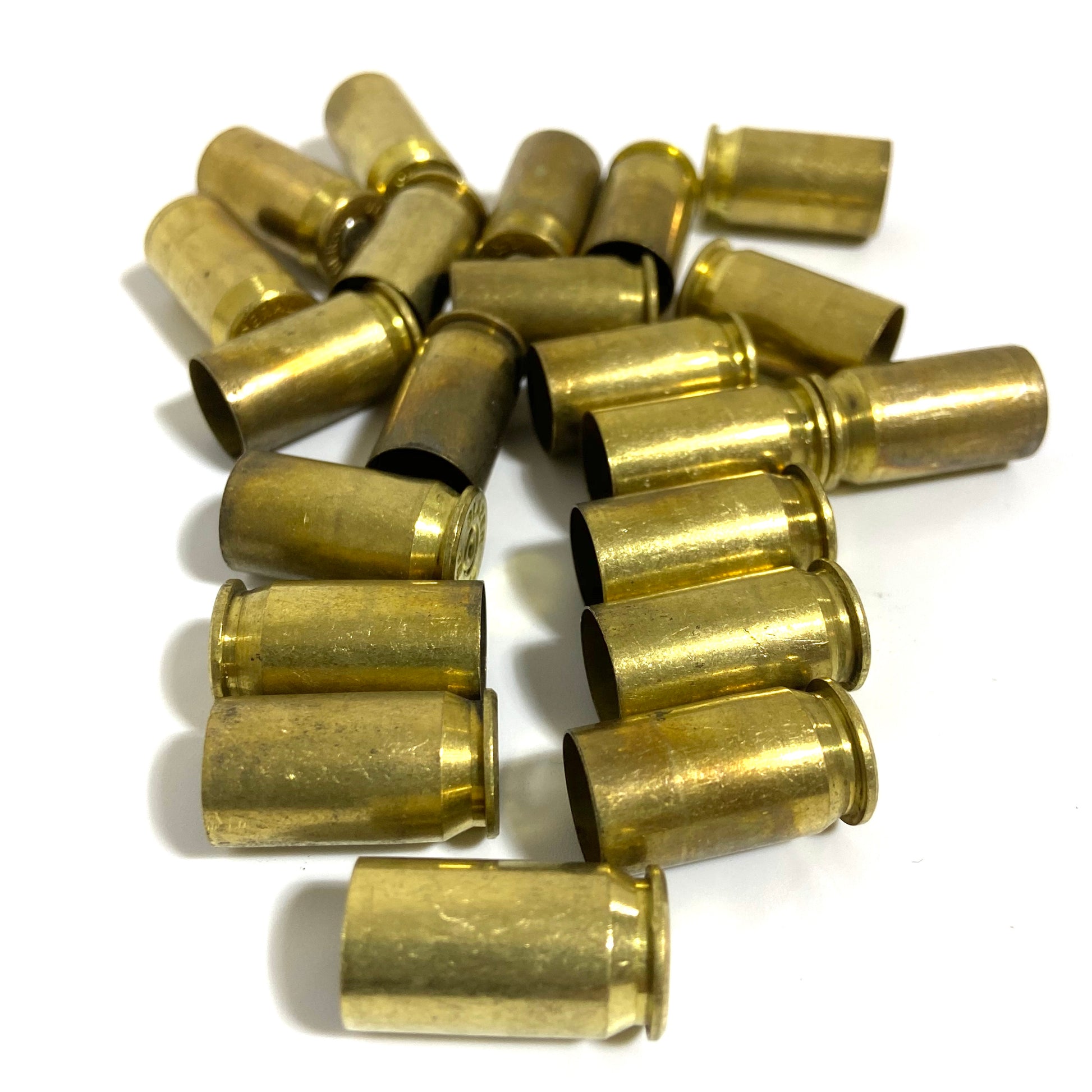 Loose pile of about 20 brass .45 ACP casings scattered on white background in mixed orientations