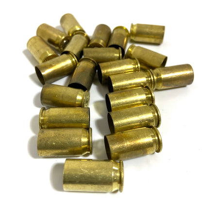Loose pile of about 20 brass .45 ACP casings scattered on white background in mixed orientations