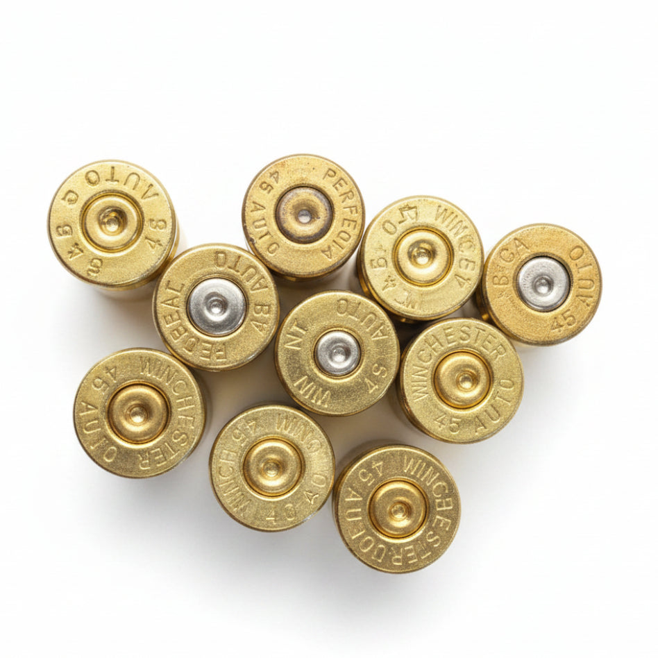 10 brass .45 ACP casings viewed from the base, showing mixed manufacturer headstamps including Winchester, Federal, and Perfecta, with both silver and brass-toned primers