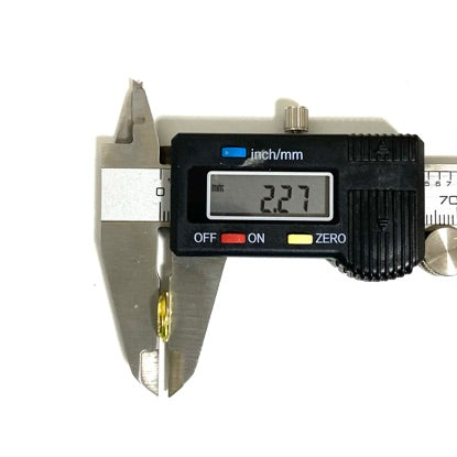 Digital caliper measuring the edge thickness of a gold bullet slice, display reading 2.27mm.