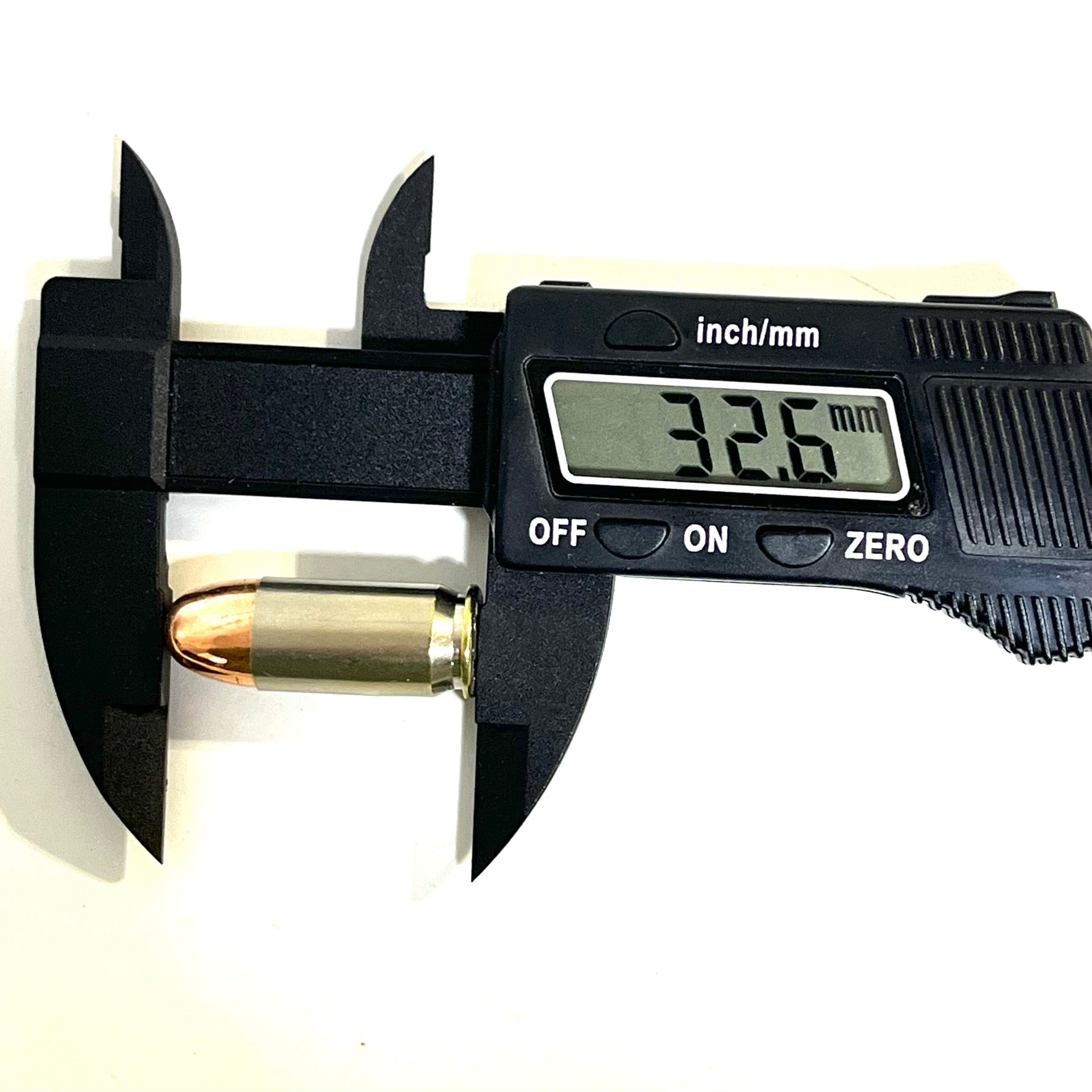 A single nickel 45 ACP dummy round measured lengthwise with a black digital caliper showing 32.6 mm.