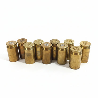 10 brass .45 ACP casings standing upright in a loose cluster on white background, primer ends facing up