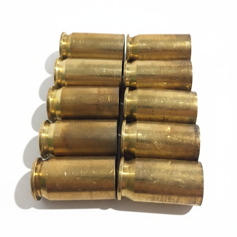 10 brass .45 ACP casings standing upright in two neat rows of five, primer ends facing up, on white background