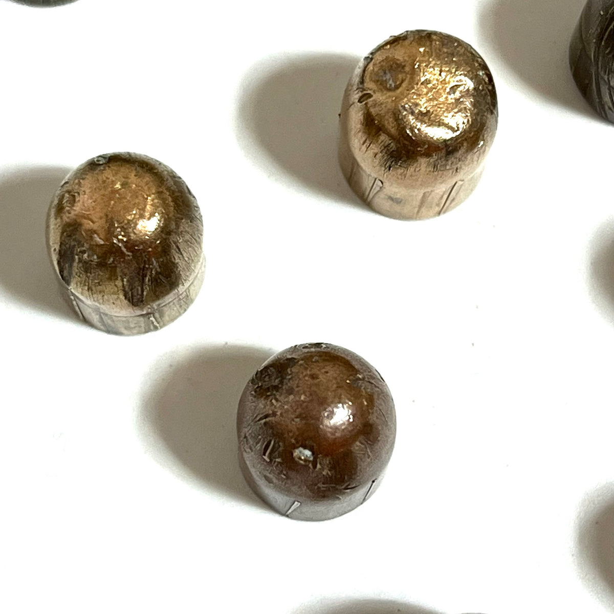 Three tarnished copper jacketed 45 ACP fired bullets standing on a white background