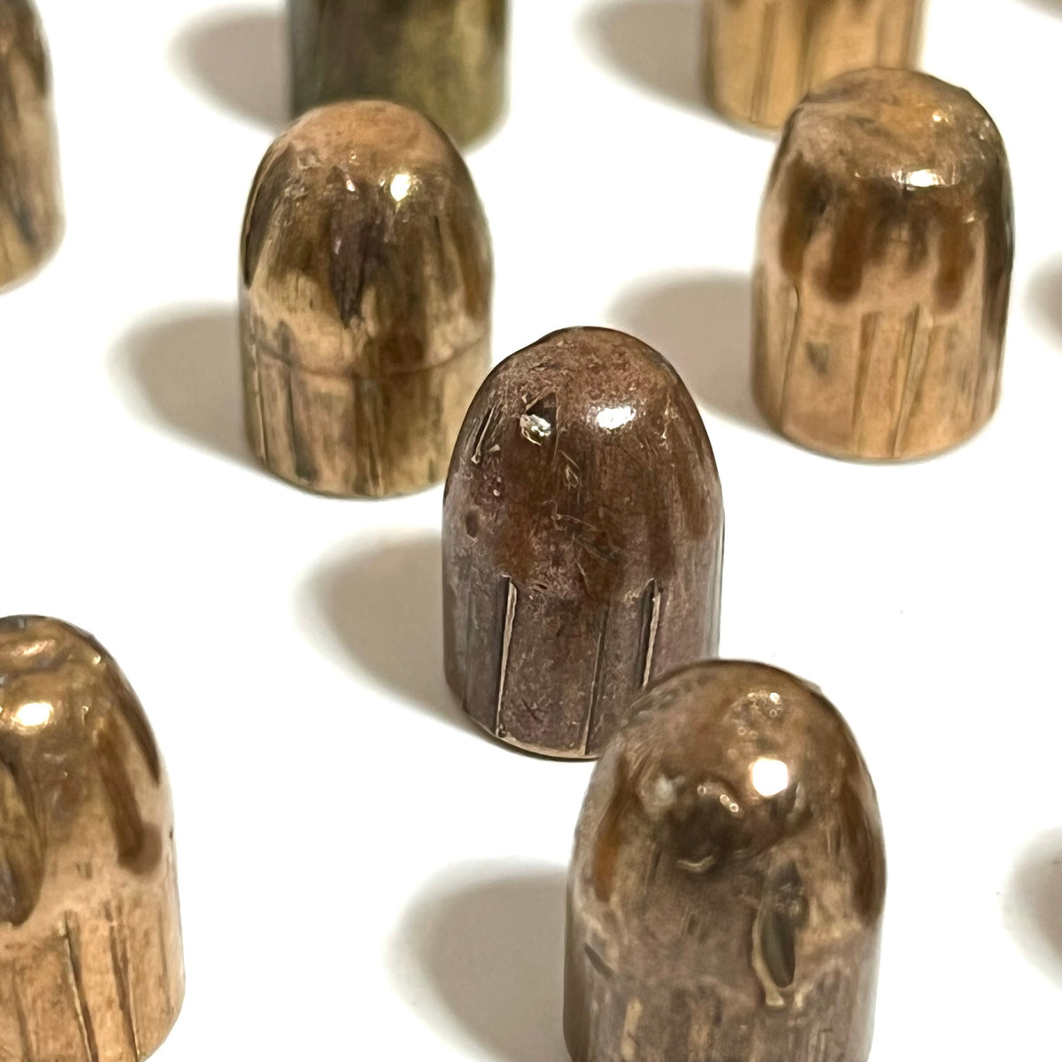 Close-up of tarnished copper jacketed 45 ACP fired bullets with flattened tips standing upright