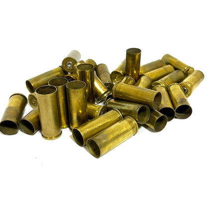 Pile of gold .45 Colt brass casings on a white background, showing open mouths and one headstamp