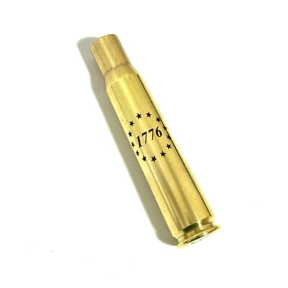 Engraved brass 50 BMG casing with '1776' and Betsy Ross 13 stars design, standing upright on a white background.