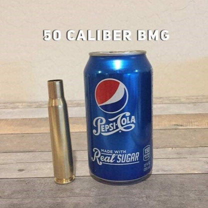 Hand-polished once-fired .50 BMG brass casing standing beside a Pepsi-Cola can for size, under 50 Caliber BMG text
