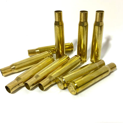 10 polished .50 BMG brass shells, 3 standing and 7 lying, grouped on a white background