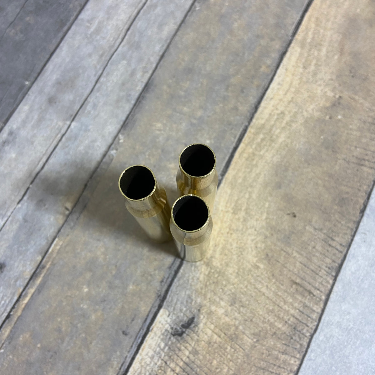 Used Bullet Casing Barrett 50 Caliber top view open case mouths on wood table