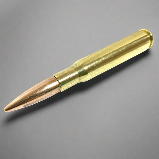 A single 50 caliber with a polished brass casing and copper bullet lying diagonally against a grey background.
