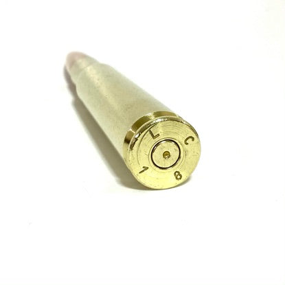 Close-up of a 50 cal dummy round paperweight showing headstamp and spent primer on a white background.