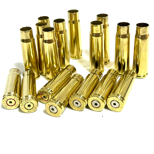 Group of once-fired brass 7.62x39 casings, drilled for jewelry crafts, arranged upright and lying on a white background.