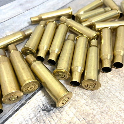 Pile of empty spent 7.62x54R Russian brass rifle casings scattered on a wood surface