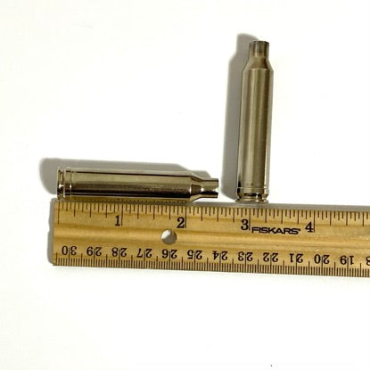 Size and dimensions measurement of an empty nickel-plated 7mm Remington Magnum rifle shell casing next to a ruler.
