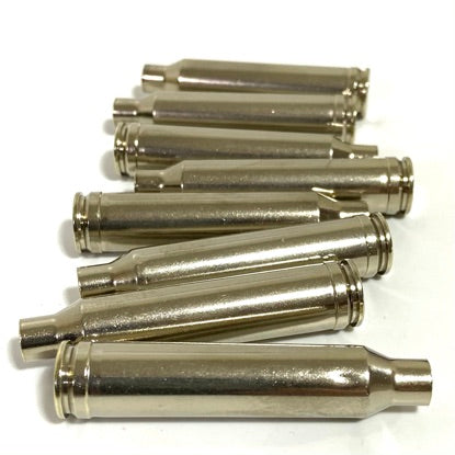 A pile of shiny nickel-plated 7mm Remington Magnum empty rifle brass casings on a white background.
