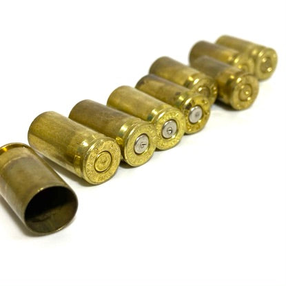 Seven spent 9mm brass casings lined up diagonally on white background showing bases and open mouth.